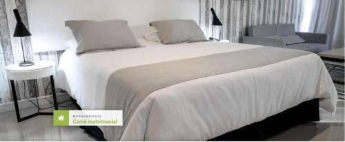 - une chambre avec un grand lit blanc et une chaise dans l'établissement Green Park Apartamento de 1amb en PB con Jardín, à Punta del Este