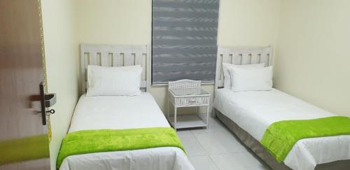 two beds with green sheets in a room at Villa 2527 San Lameer in Southbroom