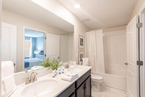 uma casa de banho com um lavatório, um WC e um espelho. em 820DSD - The Retreat at ChampionsGate em Davenport