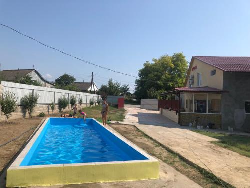 un hombre de pie junto a una piscina en un patio en Гостиный Дом Comfort, en Reni