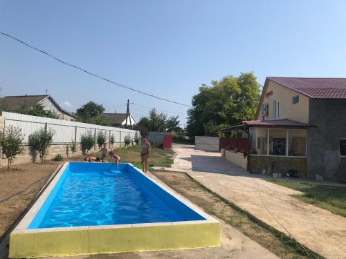 a man standing next to a swimming pool in a yard at Гостиный Дом Comfort in Reni