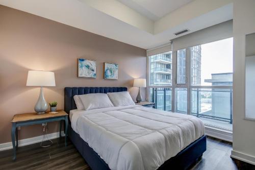 a bedroom with a large bed and a large window at The Benetton Suite - Square One 1 BR + Den + 1 Parking in Mississauga