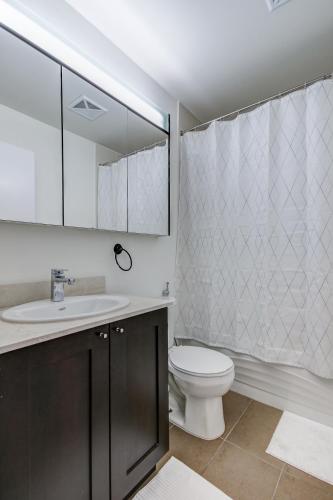 a bathroom with a toilet and a sink and a mirror at The Benetton Suite - Square One 1 BR + Den + 1 Parking in Mississauga