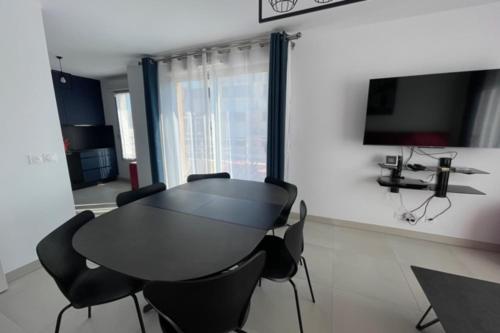 Cette chambre comprend une table et des chaises noires ainsi qu'une télévision. dans l'établissement Beautiful Bright Apt At 3 Min Walk From The Beach, à Antibes