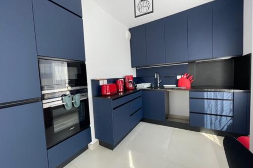 une cuisine avec des armoires bleues et des appareils rouges dans l'établissement Beautiful Bright Apt At 3 Min Walk From The Beach, à Antibes
