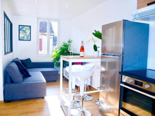 a kitchen with a refrigerator and a table and a couch at Oasis au Coeur de Ville Sens in Sens