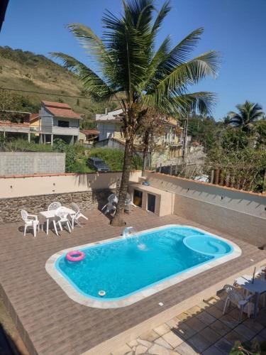 a pool with a palm tree and a table and chairs at Vale do Pontal Angra Suites in Angra dos Reis