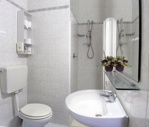 a white bathroom with a toilet and a sink at Hotel La Brezza frontemare in Lido di Jesolo