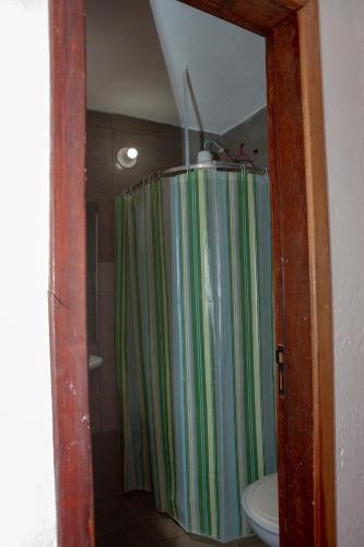 a bathroom with a green shower curtain and a toilet at Planeta Macacos in Macacos