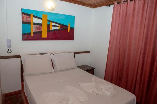 a bedroom with a bed with a painting on the wall at Planeta Macacos in Macacos