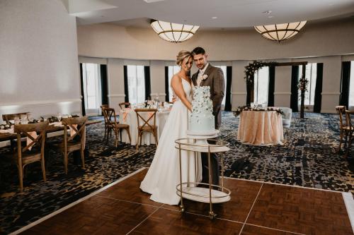 a bride and groom standing next to a wedding cake at Crowne Plaza Cleveland at Playhouse Square by IHG in Cleveland