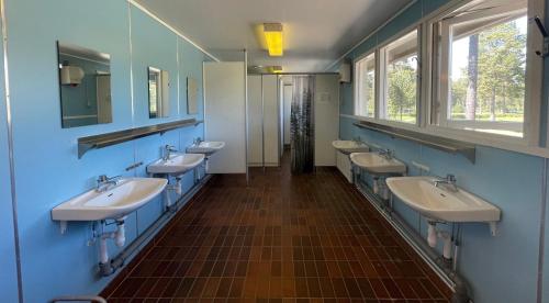 uma casa de banho com quatro lavatórios e uma fila de espelhos em Hostel Hudiksvall Malnbaden Camping em Hudiksvall