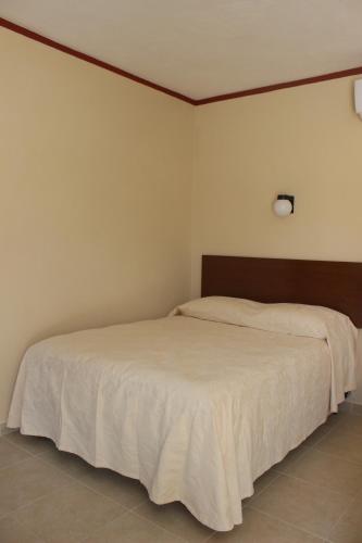 a bedroom with a large bed with white sheets at Hotel La Piramide Izamal in Izamal