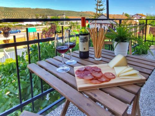 El Rancho Grande - Apartamento في ألورا: طاولة خشبية مع الجبن وكؤوس النبيذ على الشرفة