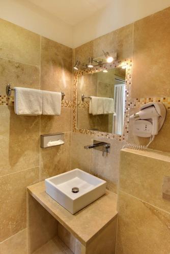 une salle de bain avec un lavabo et un miroir dans l'établissement Hôtel de la Corniche, à Bastia