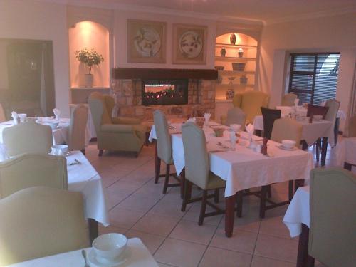 comedor con mesas y sillas y chimenea en Nautilus Guest House, en Hermanus