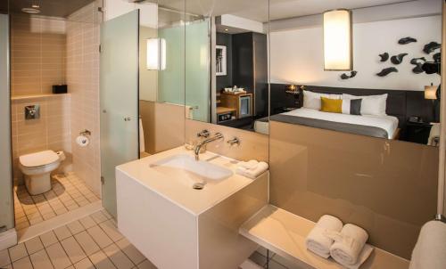 a bathroom with a sink and a toilet and a bed at Piazza Hotel Montecasino in Johannesburg