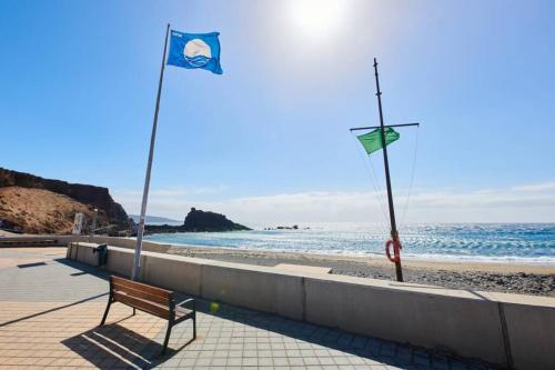 a bench sitting on top of a beach next to the ocean at Sarahs Kite Vivienda Vacacional en Playa del Burrero in Playa del Burrero