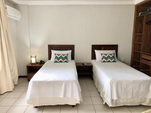 a bedroom with two beds with white sheets and sidx sidx sidx at Blue Marlin Cotovelo - Vista Vale - Reformado in Parnamirim