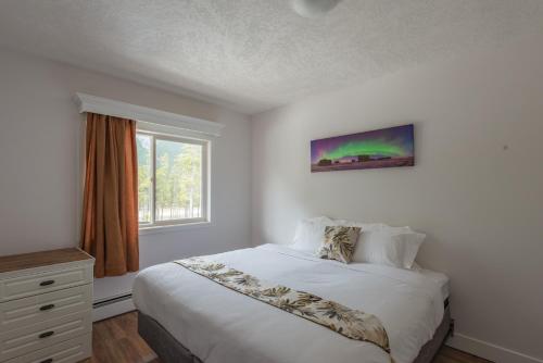 um quarto branco com uma cama e uma janela em David Thompson Resort em Cline River