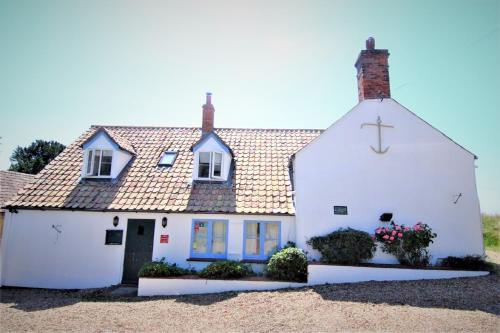 a white house with a cross on the roof at The Anchor in Sutton