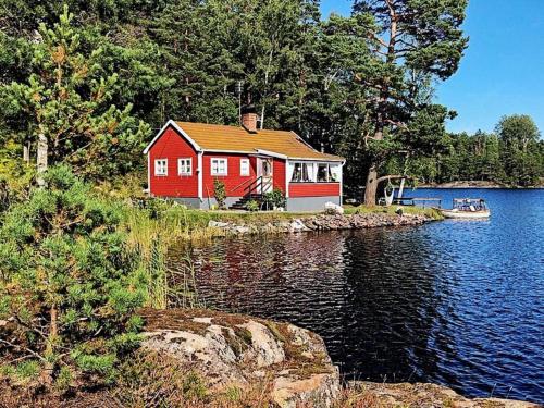 a red house on the shore of a lake at 5 person holiday home in KERSBERGA in Åkersberga