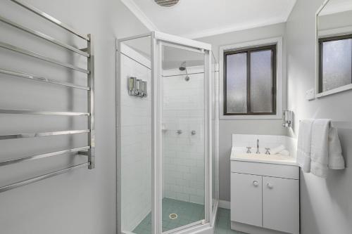 a white bathroom with a shower and a sink at Cottages On Mount View in Mount View