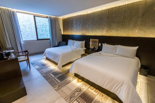 a hotel room with two beds and a window at Casa Naila Hotel Boutique in Oaxaca City