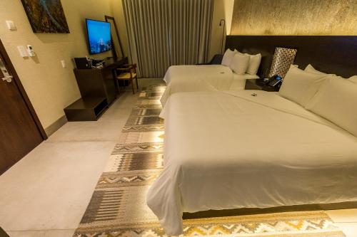 a hotel room with two beds and a television at Casa Naila Hotel Boutique in Oaxaca City