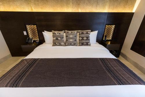 a bedroom with a large white bed with a black headboard at Casa Naila Hotel Boutique in Oaxaca City