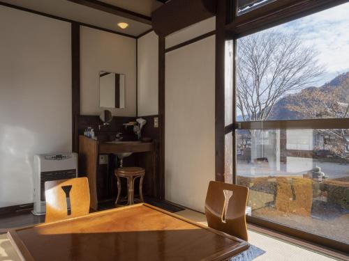 a dining room with a table and chairs and a large window at Shojuen in Minakami
