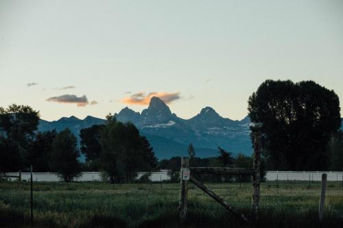 a field with a fence and mountains in the background at Teton Peaks Resort in Tetonia