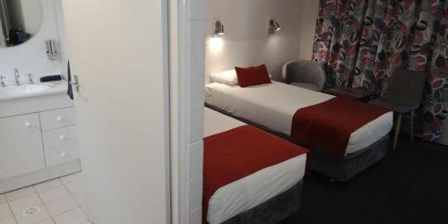 a bedroom with a bed and a bathroom with a sink at Lake Munmorah Motel in Lake Munmorah