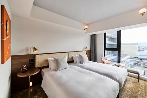 two beds in a hotel room with a large window at The Royal Park Canvas - Kyoto Nijo in Kyoto