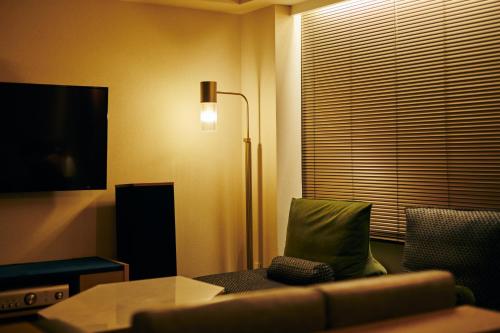 a living room with a couch and a tv and a lamp at NOHGA HOTEL AKIHABARA TOKYO in Tokyo