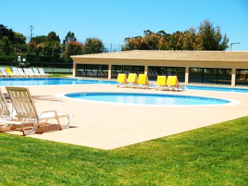 a swimming pool with lounge chairs and a building at Apartamentos Paraíso Sol da Rocha in Portimão