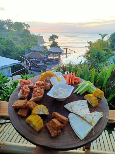 a plate of food on a table near the beach at Milo's Home in Jimbaran