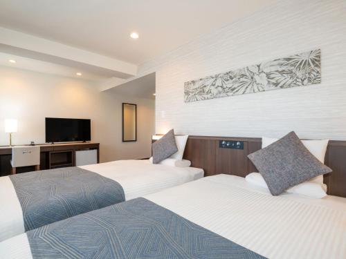 a hotel room with two beds and a flat screen tv at ART HOTEL Miyazaki Sky Tower in Miyazaki