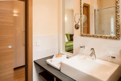 ein Bad mit einem Waschbecken und einem Spiegel in der Unterkunft Hotel Residence Pernhof in Tramin an der Weinstraße
