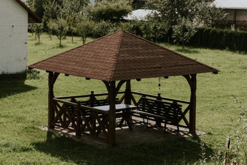 a wooden gazebo with a table and two benches at Zielone Zagrody - Cieplice in Adamówka