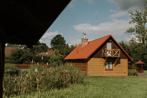 a small wooden house with a red roof at Zielone Zagrody - Cieplice in Adamówka