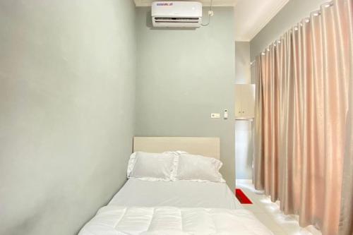 a small bedroom with a bed and a window at Pelangi Guest House Palembang RedPartner in Talang Kelapa