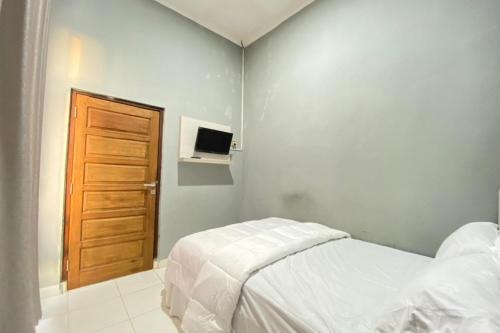 a bedroom with a bed and a wooden door at Pelangi Guest House Palembang RedPartner in Talang Kelapa