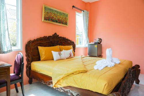 a bedroom with a bed with an orange wall at Iris Homestay in Ban Muang