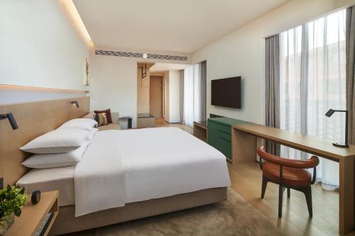 a hotel room with a bed and a desk and a television at Hyatt Place Jingdezhen Taoxichuan in Jingdezhen
