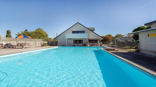 a large blue swimming pool in front of a house at Holdens Bay Holiday Park in Rotorua