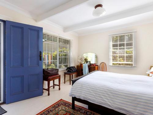 a bedroom with a bed and a blue door at Garden Cottage in Tea Gardens