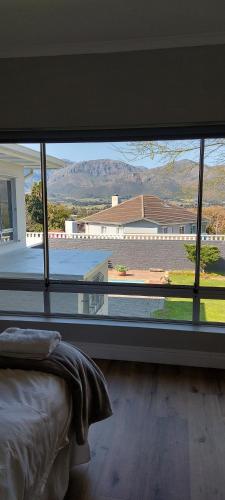 a bedroom with a large window with a view of a house at Kortrijk Paarl Self Catering in Paarl