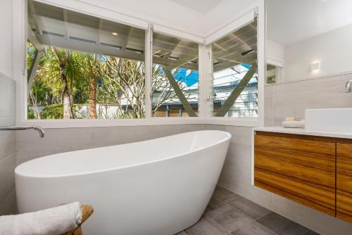 a white bathroom with a tub and a window at Coorabell Estate in Coorabell Creek