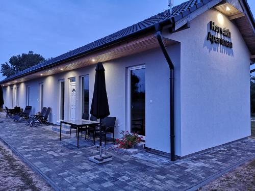 a building with a table and a umbrella in front of it at Horváth Apartmanok in Mórahalom